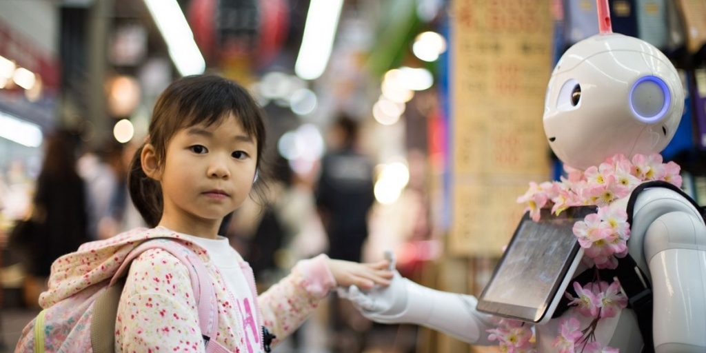Ein Mädchen und Roboter geben sich die Hand. Foto aufgenommen auf einem Markt in Japan.